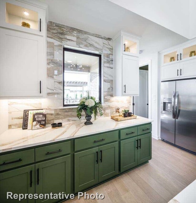 kitchen featuring tasteful backsplash, green cabinets, stainless steel fridge with ice dispenser, white cabinets, and light wood-type flooring