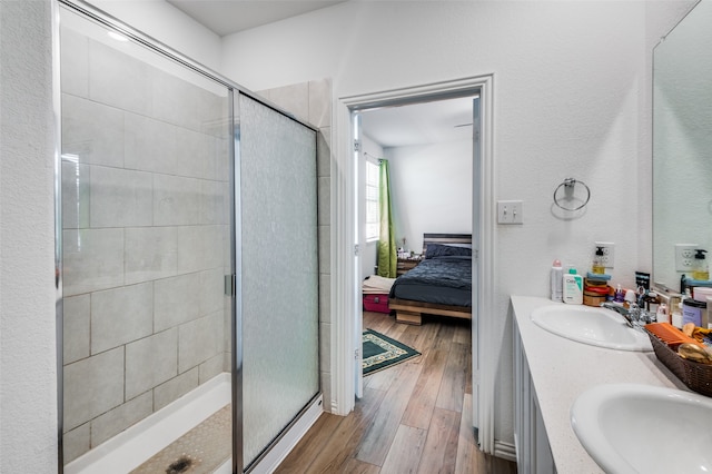 bathroom with hardwood / wood-style floors, vanity, and a shower with shower door