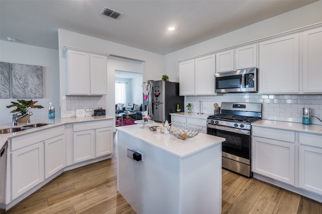 kitchen with light wood-type flooring, stainless steel appliances, white cabinetry, and sink