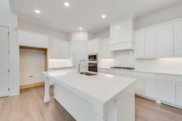 kitchen featuring white cabinetry, stainless steel appliances, and a center island with sink