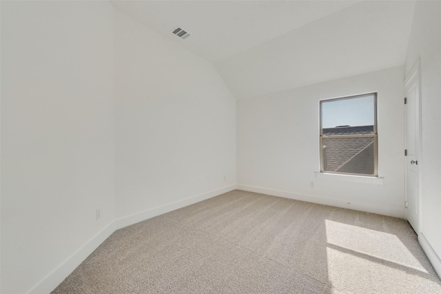 carpeted spare room with lofted ceiling