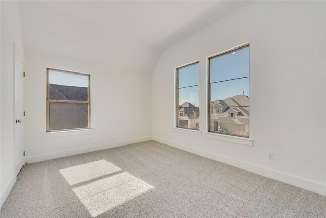 unfurnished room featuring lofted ceiling and light carpet