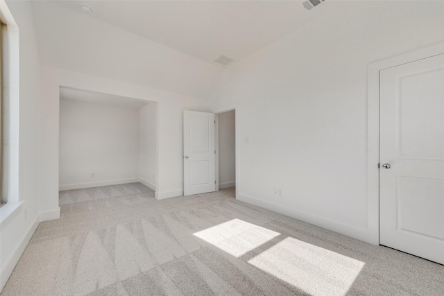 carpeted spare room with lofted ceiling