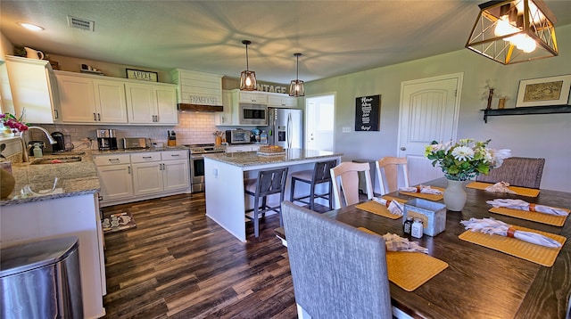 dining space featuring sink, dark hardwood / wood-style floors, and an inviting chandelier