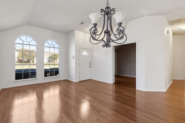 interior space featuring wood-type flooring, lofted ceiling, a textured ceiling, and a notable chandelier