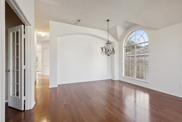 unfurnished dining area with dark hardwood / wood-style flooring, a textured ceiling, and an inviting chandelier