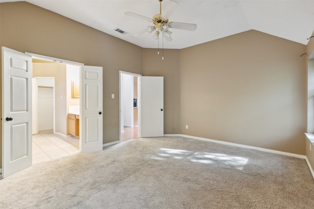 unfurnished bedroom with ensuite bath, ceiling fan, light carpet, and lofted ceiling