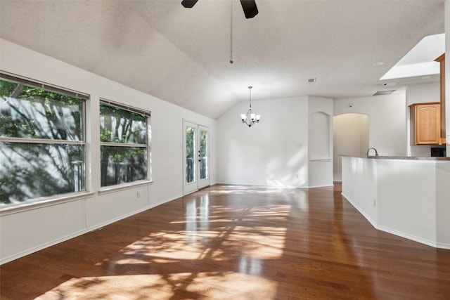 unfurnished living room featuring dark hardwood / wood-style flooring, a textured ceiling, and vaulted ceiling