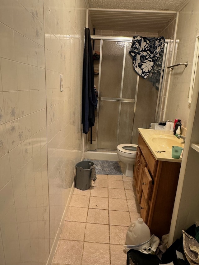 bathroom featuring tile patterned flooring, vanity, toilet, and walk in shower