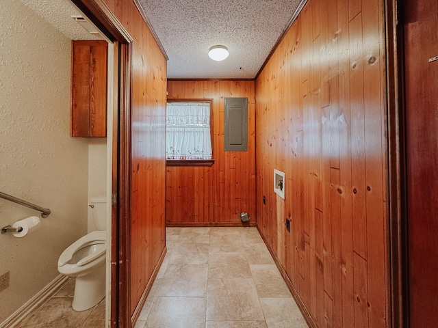 bathroom featuring wood walls, electric panel, toilet, ornamental molding, and a textured ceiling