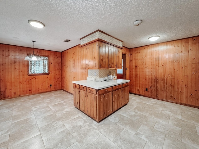 kitchen featuring pendant lighting, wood walls, and a textured ceiling