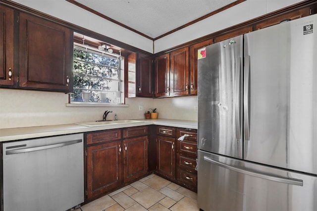 kitchen with dark brown cabinetry, sink, stainless steel appliances, crown molding, and a textured ceiling