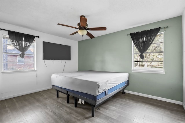 bedroom featuring wood-type flooring, a textured ceiling, and ceiling fan