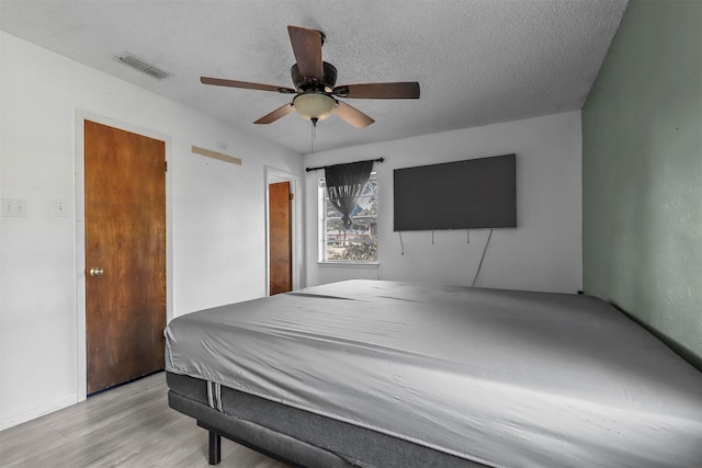 bedroom with ceiling fan, light hardwood / wood-style floors, and a textured ceiling