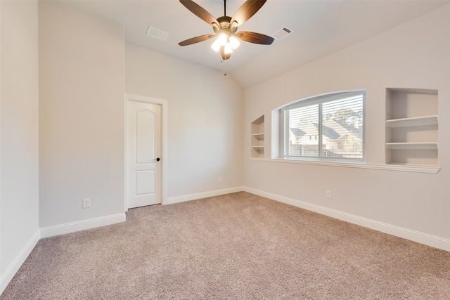 spare room featuring built in features, carpet floors, vaulted ceiling, and ceiling fan