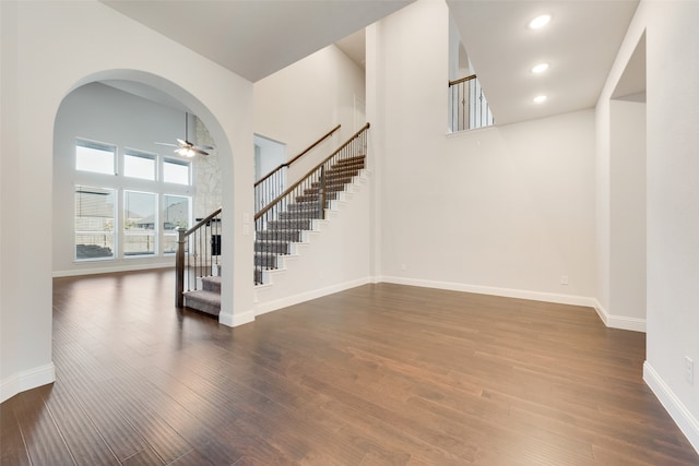 interior space featuring ceiling fan, a towering ceiling, and dark hardwood / wood-style floors