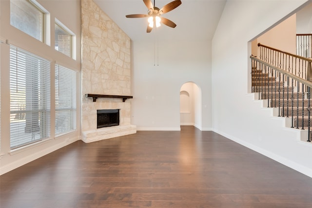 unfurnished living room featuring a fireplace, high vaulted ceiling, ceiling fan, and dark wood-type flooring