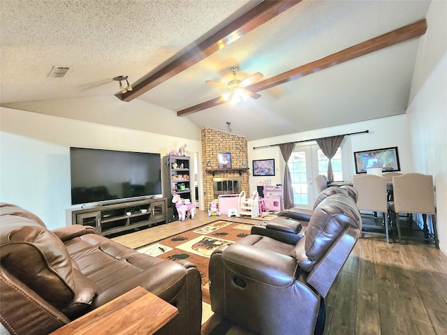 living room with dark wood-type flooring, a brick fireplace, vaulted ceiling with beams, ceiling fan, and a textured ceiling