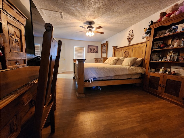 bedroom with a textured ceiling, ceiling fan, and dark hardwood / wood-style floors