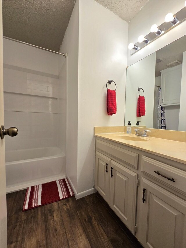 bedroom with ceiling fan, wood-type flooring, and a textured ceiling