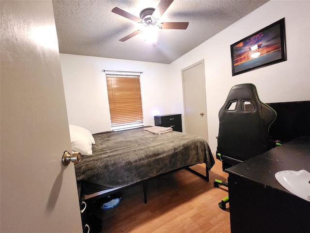 bedroom featuring ceiling fan, wood-type flooring, and a textured ceiling