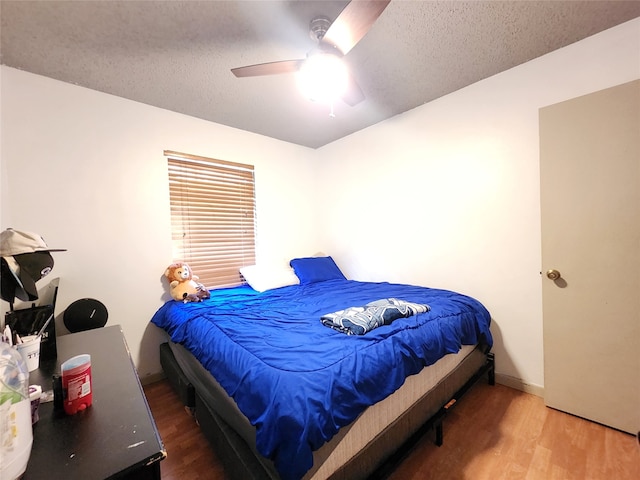 bedroom featuring ceiling fan, wood-type flooring, and a textured ceiling