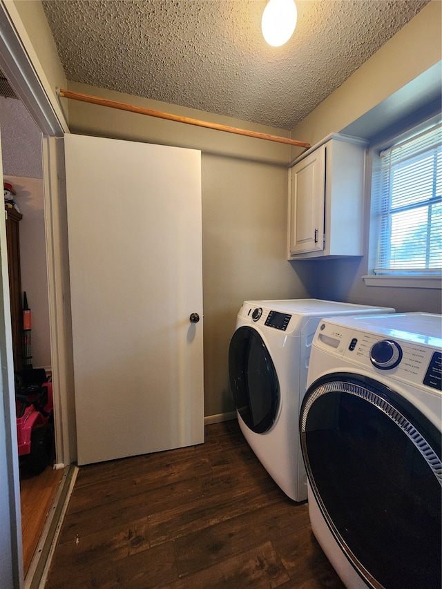 laundry area featuring washing machine and clothes dryer, dark wood-type flooring, cabinets, and a textured ceiling