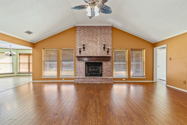 unfurnished living room featuring visible vents, a ceiling fan, lofted ceiling, wood finished floors, and a brick fireplace