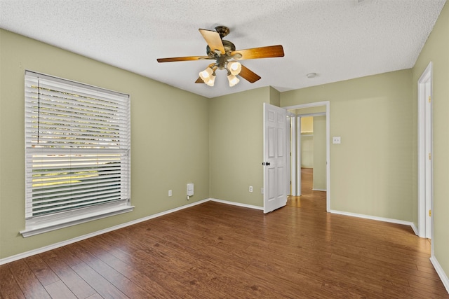 empty room featuring dark wood-style flooring, ceiling fan, a textured ceiling, and baseboards