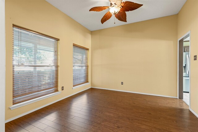 spare room with dark wood-style floors, baseboards, and a ceiling fan