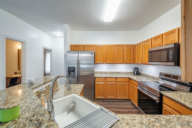 kitchen featuring dark hardwood / wood-style flooring, light stone countertops, sink, and appliances with stainless steel finishes