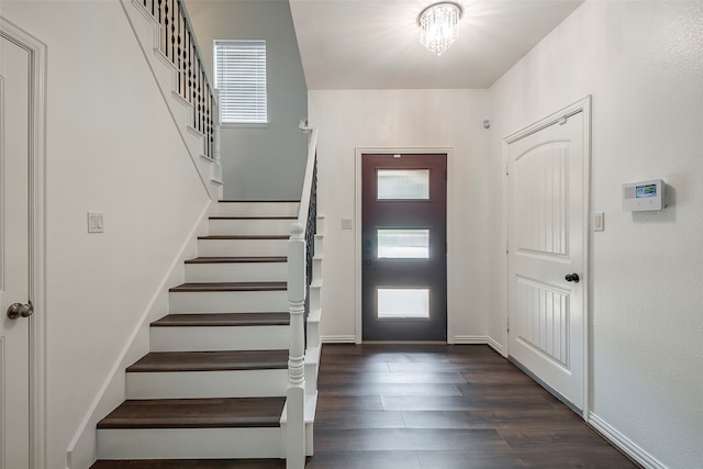 foyer featuring dark wood-type flooring and an inviting chandelier