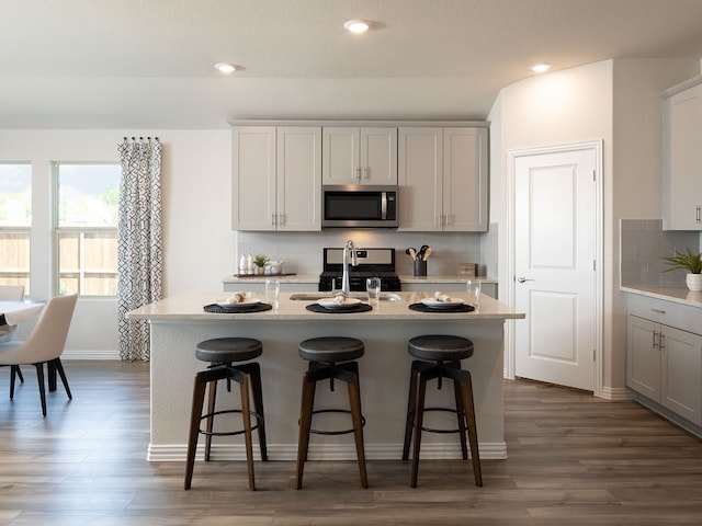 kitchen featuring dark hardwood / wood-style flooring, stainless steel appliances, and a kitchen island with sink