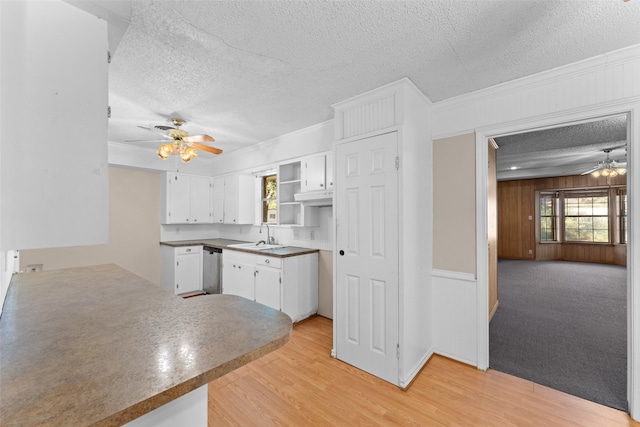 kitchen featuring stainless steel dishwasher, ornamental molding, a textured ceiling, light hardwood / wood-style floors, and white cabinetry