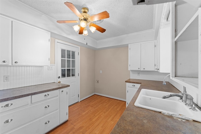 kitchen featuring white cabinets, ceiling fan, ornamental molding, a textured ceiling, and light hardwood / wood-style floors