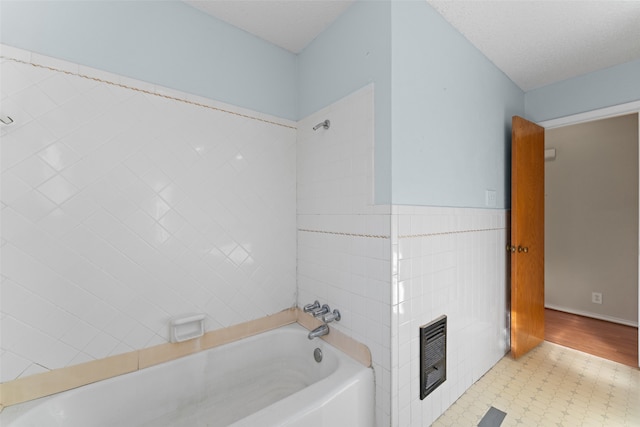 bathroom featuring a washtub, a textured ceiling, and tile walls