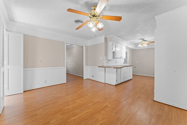 unfurnished living room with ceiling fan, a textured ceiling, and light hardwood / wood-style flooring