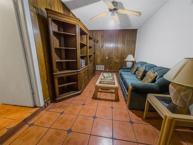 living room featuring tile patterned flooring, vaulted ceiling, ceiling fan, and wood walls