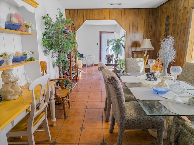 dining room with tile patterned flooring and wood walls