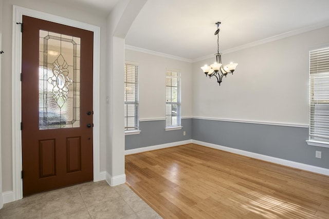 foyer featuring crown molding, light hardwood / wood-style flooring, and a chandelier