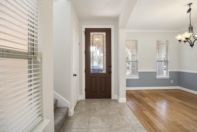 foyer entrance with light hardwood / wood-style floors, crown molding, and a chandelier