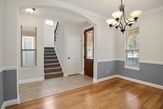 empty room featuring plenty of natural light, light hardwood / wood-style floors, ornamental molding, and an inviting chandelier