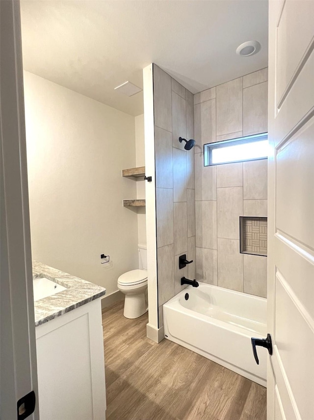 full bathroom featuring toilet, vanity, hardwood / wood-style floors, and tiled shower / bath