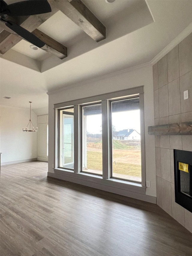 unfurnished living room with a fireplace, beam ceiling, light wood-type flooring, and ornamental molding