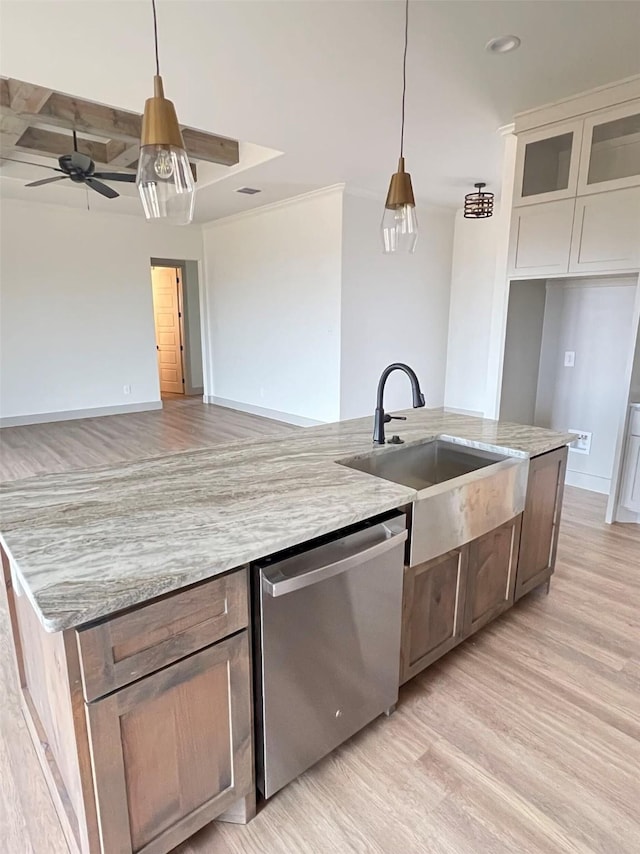 kitchen with stainless steel dishwasher, sink, hanging light fixtures, and light stone countertops