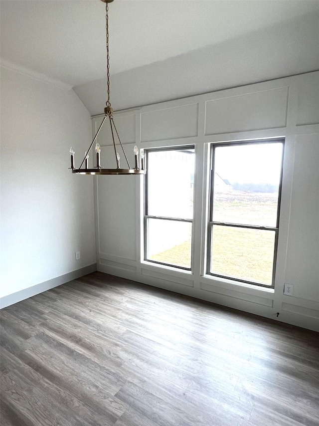 unfurnished dining area featuring vaulted ceiling, hardwood / wood-style floors, an inviting chandelier, and plenty of natural light