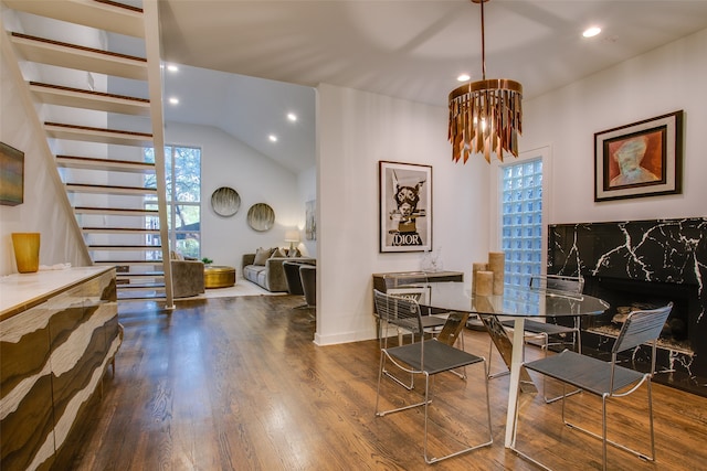 dining room with hardwood / wood-style flooring, vaulted ceiling, and a notable chandelier