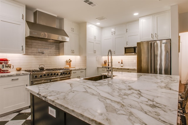 kitchen featuring white cabinets, high quality appliances, and wall chimney range hood