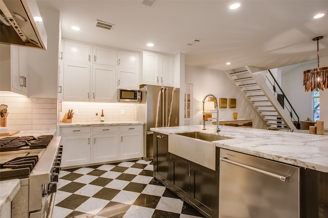 kitchen featuring premium appliances, white cabinetry, hanging light fixtures, and ventilation hood