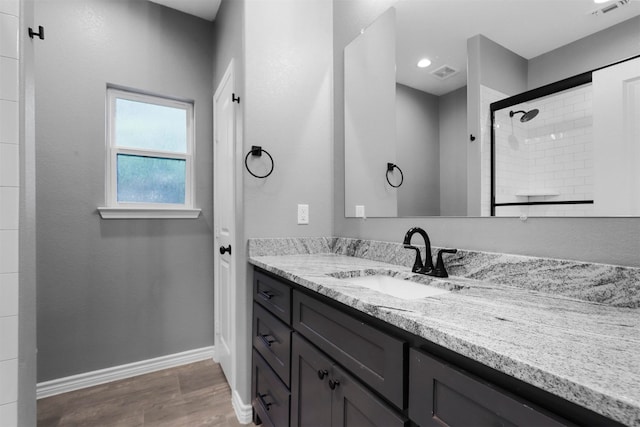 bathroom with hardwood / wood-style flooring, vanity, and a tile shower